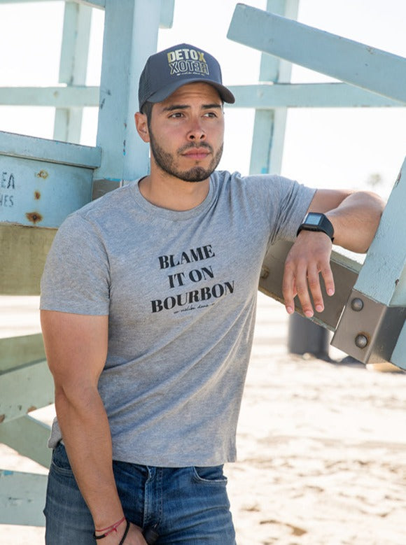 man standing in front of a lifegaurd tower wearing grey tee that reads Blame It On The Bourbon